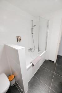 y baño blanco con ducha y aseo. en Les Cerisiers - Appartement Cosy au Centre de Namur, en Namur