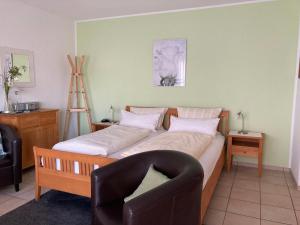 a bedroom with a large bed with a chair and a chair at Landhaus-Apartments in Wattenheim