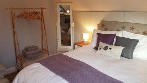 um quarto com uma grande cama branca com almofadas roxas em Post Office Row Apartment and garden em Crickhowell