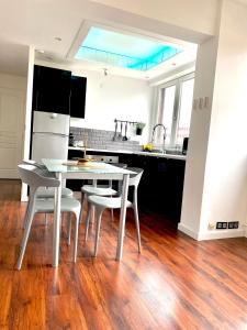 uma cozinha com uma mesa branca e cadeiras brancas em LE CARDINAL, appartement avec parking privé, gare, centre ville, em Annecy