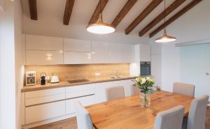 una cucina con tavolo in legno e armadietti bianchi di Chalet-Appartement mit Penthouse Flair a Bad Hofgastein