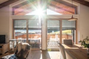 a living room with a large window with the sun shining through at Chalet-Appartement mit Penthouse Flair in Bad Hofgastein