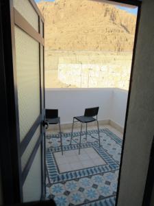 two chairs on a porch with a view of the desert at Unique&Warmy place in the Dead Sea in Ovnat