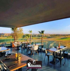 um restaurante com mesas e cadeiras e vista para um campo de golfe em Prestigia Golf City Marrakech em Marrakech