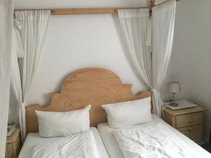 - une chambre avec 2 lits avec des draps blancs et une tête de lit en bois dans l'établissement Haus Anker Wohnung 9, à Norderney