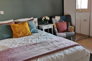 Un dormitorio con una cama con almohadas de colores y una silla. en Pretty and quiet studio, with wifi and parking en Limassol