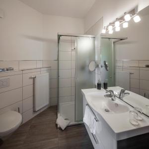a bathroom with a sink and a shower and a toilet at Hotel Pfaffenhofen in Schwabenheim