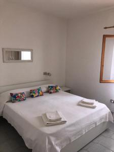 a white bedroom with a bed with towels on it at Centro e Cinta beach free bikes in San Teodoro