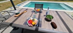 a table with food on it next to a swimming pool at Villa Cosy avec piscine privative in Ghisonaccia