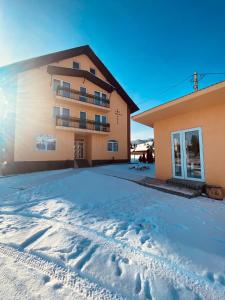 um edifício com neve em frente em Casa Raluca em Arieşeni