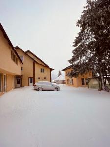 ein Auto parkt auf einem schneebedeckten Parkplatz in der Unterkunft Casa Raluca in Arieşeni