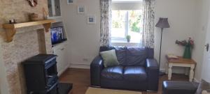 a living room with a leather couch and a fireplace at Cromlech Cottage in Portnoo