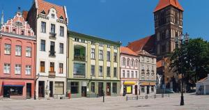 un grupo de edificios en una calle con una torre de reloj en Apartament Skandia Blue en Toruń