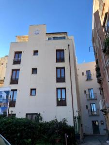 een wit gebouw met zwarte ramen op een straat bij La Colombaia in Trapani