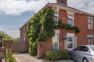 una casa di mattoni rossi con una macchina parcheggiata di fronte di The Studio Christchurch B&B Luxury Garden Room a Christchurch