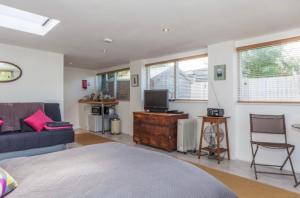 1 dormitorio con cama, sofá y TV en The Studio Christchurch B&B Luxury Garden Room, en Christchurch