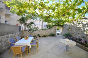 eine Terrasse mit einem Tisch, Stühlen und einer Steinmauer in der Unterkunft Stone house Dobrota in Kotor