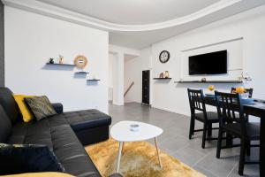 a living room with a black couch and a table at Appart T3 Spacieux & Cosy Face à la gare in Lens