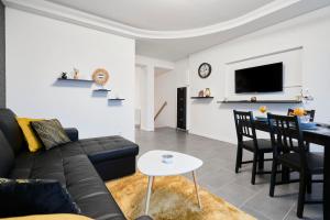 ein Wohnzimmer mit einem schwarzen Sofa und einem Tisch in der Unterkunft Appart T3 Spacieux & Cosy Face à la gare in Lens