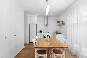 a white kitchen with a wooden table and white chairs at Foxmount Estate - Astrid in Mount Gambier