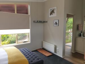 a bedroom with a bed and a chair and windows at Lakeside Studio in Jindabyne