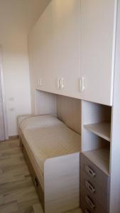 niewielka sypialnia z łóżkiem i białymi szafkami w obiekcie STELLA MARIS Sardinia w mieście La Caletta
