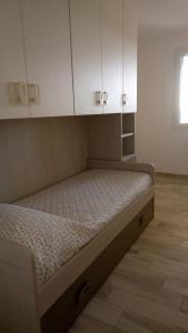 łóżko w pokoju z białymi szafkami w obiekcie STELLA MARIS Sardinia w mieście La Caletta