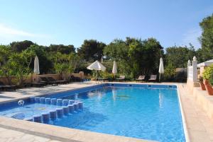 a swimming pool with chairs and umbrellas at Hostal Restaurante Pou des Lleó in Sant Carles de Peralta