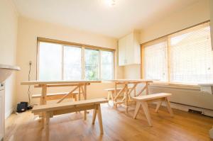 una stanza con tavoli e panche in una stanza con finestre di TOMA HOUSE - Vacation STAY 8723 a Sapporo