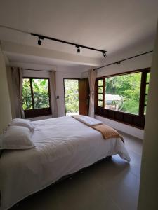 a bedroom with a large white bed with windows at Hotel Boutique Albania in Otanche