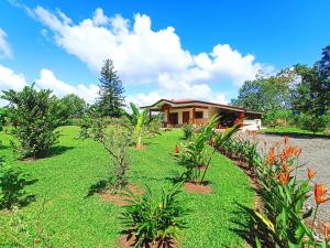 ein Haus mit einem grünen Hof mit Pflanzen davor in der Unterkunft Villa Ceiba in Fortuna