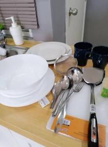 a counter top with white plates and spoons on it at Cozy Studio house /Soho Unit Near Kampar Utar in Kampar