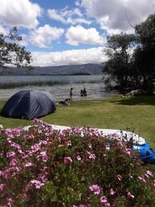 uma tenda sentada na relva perto de um corpo de água em Camping Los Balcones em Cuítiva