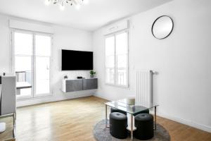 a white living room with a table and a tv at Disneyland-Paris 6pers,Parking, Wifi, in Serris