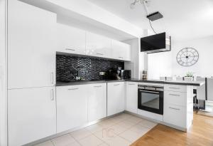 a white kitchen with white cabinets and black appliances at Disneyland-Paris 6pers,Parking, Wifi, Netflix in Serris