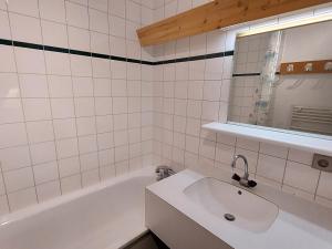 a white tiled bathroom with a sink and a mirror at Appartement Valmorel, 1 pièce, 4 personnes - FR-1-356-391 in Les Avanchers