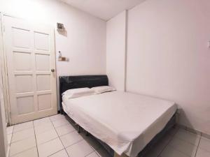 a small white room with a bed and a door at Budget stay easy access to Timberland Medical Centre,Batu 3 Kuching By Natol-Hong Kong in Kuching