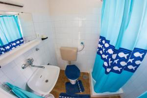 a bathroom with a toilet and a blue shower curtain at Apartments Stefanovski Paradiso in Veli Lošinj
