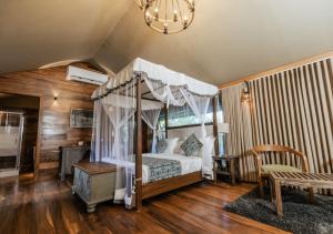 um quarto com uma cama de dossel e piso em madeira em Tribe Yala - Luxury Camping em Yala