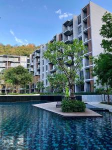 a building with a tree in front of a swimming pool at The Khao Yai in Phayayen