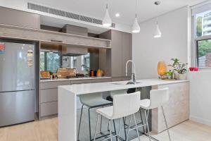 a kitchen with a white counter and stools at Cool Coastal Pad with Panoramic Water Views in Gosford