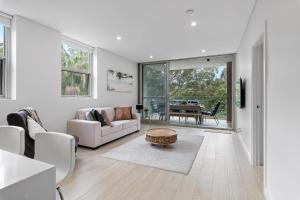 a white living room with a couch and a table at Cool Coastal Pad with Panoramic Water Views in Gosford