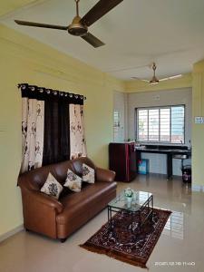 a living room with a leather couch and a glass table at Riddhi Sea View Bungalow in Ratnagiri
