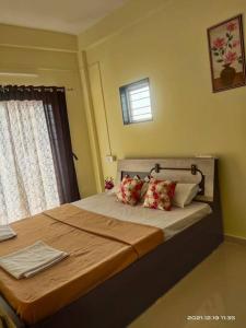 een slaapkamer met een bed met kussens en een raam bij Riddhi Sea View Bungalow in Ratnagiri