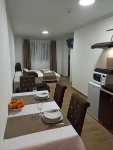 ein Wohnzimmer mit einem Tisch und Stühlen sowie eine Küche in der Unterkunft Lela Kop in Kopaonik