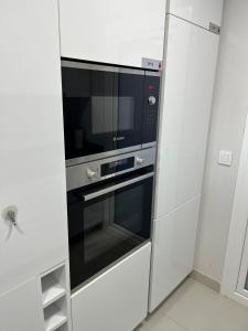 a microwave oven in a kitchen with white cabinets at Sea View Apartment Arenal Beach Calpe in Calpe
