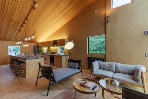 a living room with a couch and a kitchen at Foxwood E by H2 Life in Niseko