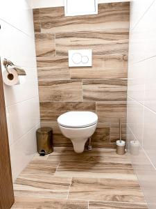 a bathroom with a toilet and wooden wall at Apartmán Rajecké Teplice in Žilina