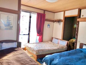 a bedroom with two beds and a window at Ocean Lovers Home in Miyazaki