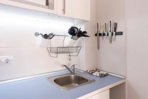 eine Küchentheke mit einer Spüle und Küchenutensilien in der Unterkunft LU&CIA Malagueta 9 in Málaga